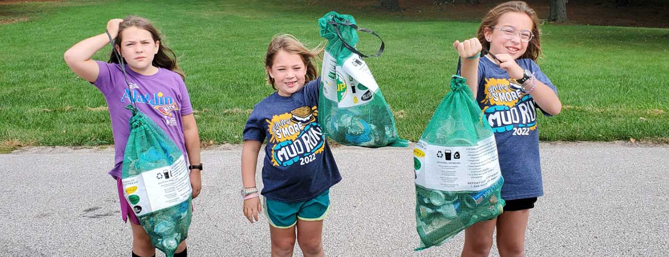 volunteer clean up, three kids with garbage collecting bags